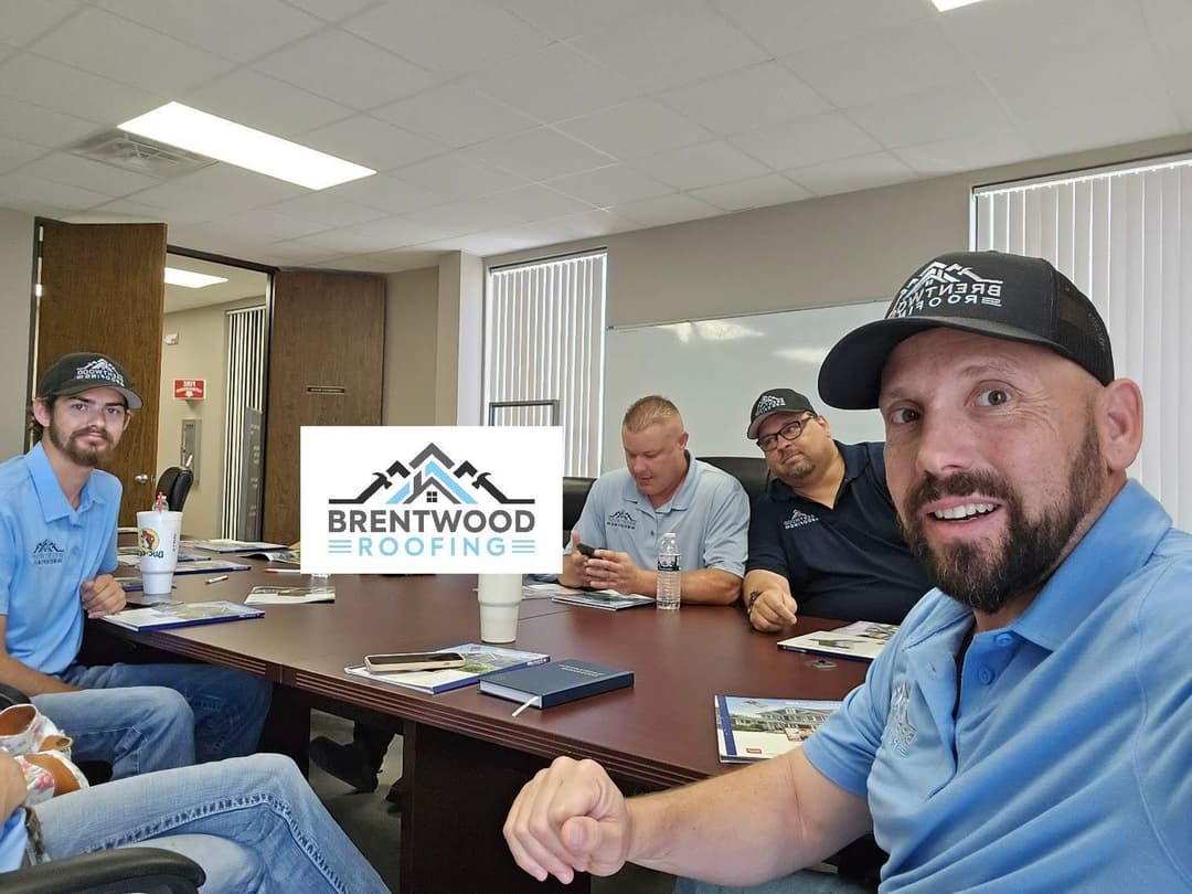 Team meeting at Brentwood Roofing, discussing projects around a conference table.