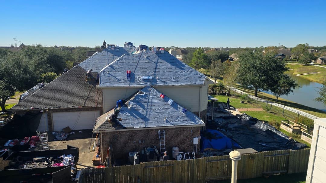 Roofing contractors installing a new roof on a residential building in a sunny neighborhood.