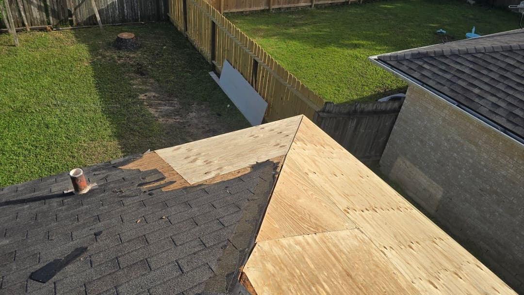 Roof repair process with plywood on a sloped roof, backyard view and fencing visible.