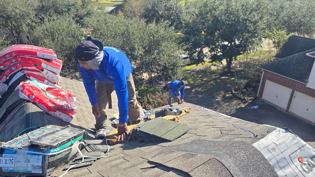 Roofers installing shingles on a residential roof, with materials and tools visible.