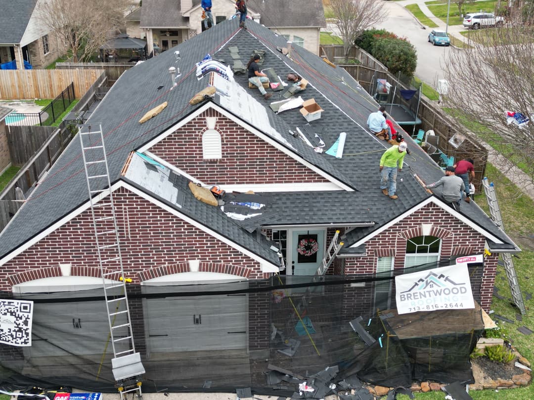 Roofing crew working on a home with tools and materials visible on the rooftop.