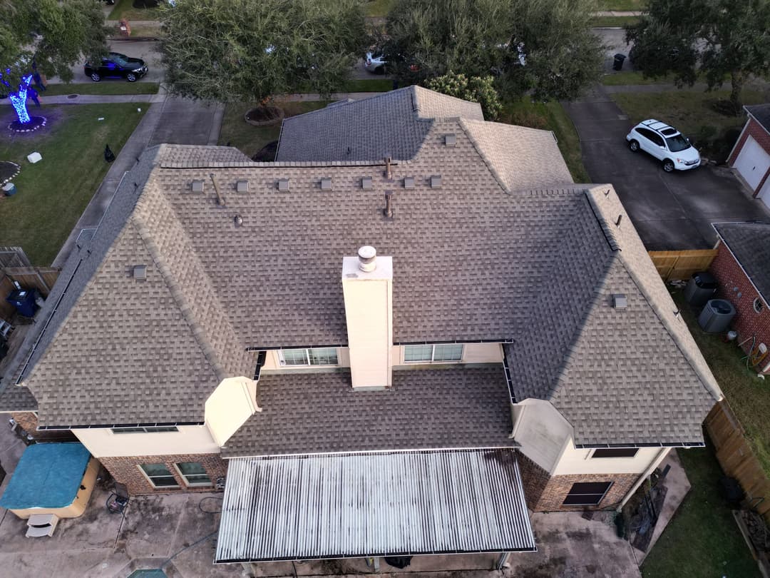 Aerial view of a residential home with a multi-pitched roof and outdoor patio area.