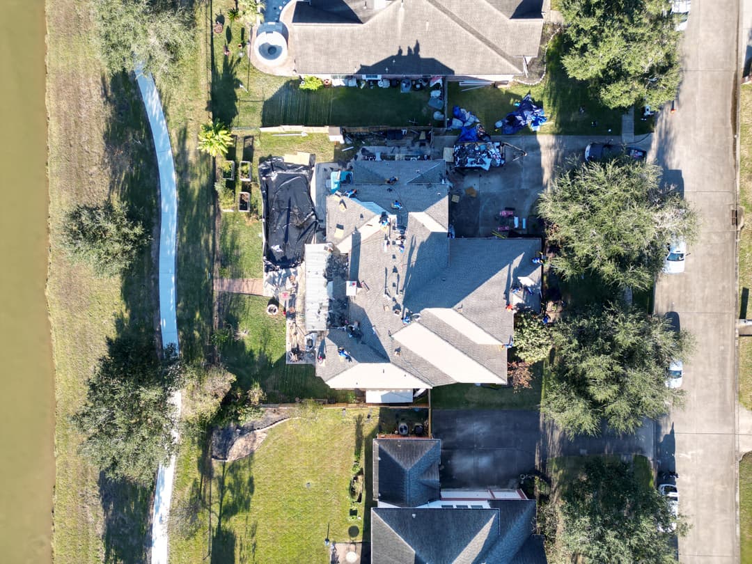 Aerial view of a residential neighborhood with houses, greenery, and a nearby waterway.